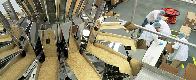 Aerial view of rice equipment filled with rice and 4 employees working on the production floor.