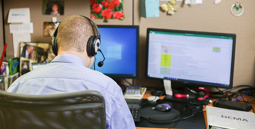 A man in a button down shirt with his back to the camera types on a computer.